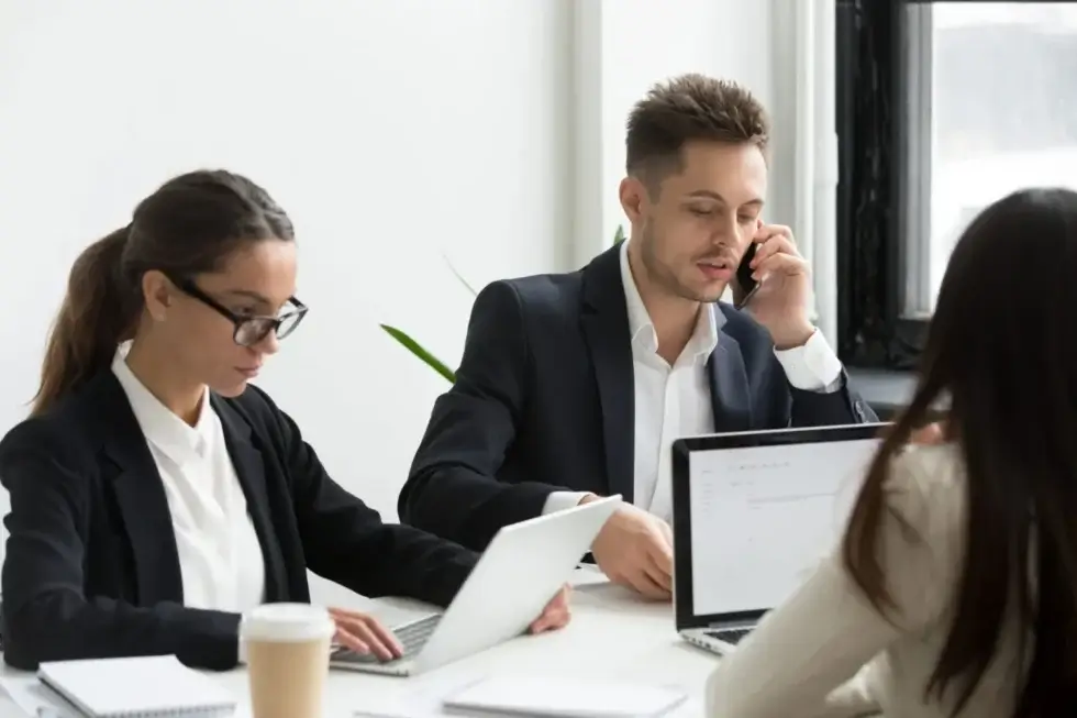 Employees working on laptops during a collaborative office meeting